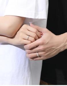 Close-up of minimalist S925 silver couple rings with heart-shaped stone on hands