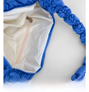 Close-up of the internal zipped pocket and white fabric lining inside the blue cloud bag