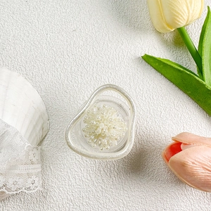 Detailed view of flower-shaped pearl phone grip on a white textured background