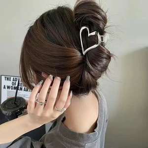 Close-up of a high-polish silver heart-shaped metal hair claw clip in an elegant hairstyle