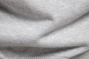 Detailed macro view of light gray V-neck knit sweater fabric showing soft texture
