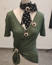 Detail of owl brooch and pearl scarf clip worn on a model with green V-neck shirt