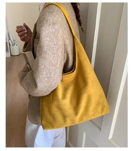 Close-up of yellow suede tote bag on model's shoulder in professional indoor lighting