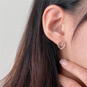 Minimalist 925 sterling silver hollow heart stud earrings worn by model on ear