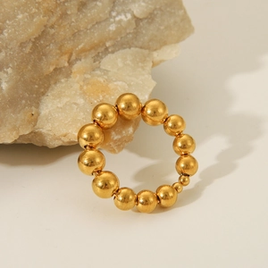 Minimalist 18K gold plated stainless steel beaded ring set against a natural stone background