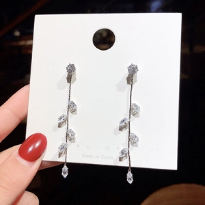 Close-up of long silver tassel earrings with zircon leaves on a display card