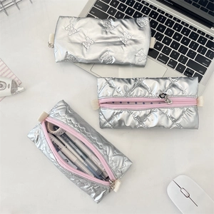 Silver PU leather pencil cases with bow embossing and polka dot lining on white desk