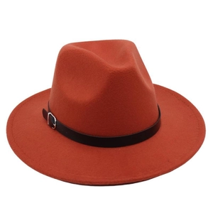 Close-up of burnt orange fedora hat featuring a black leather band and silver metal buckle
