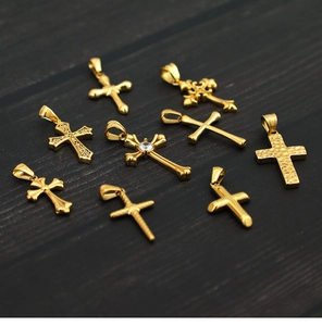 Detailed view of assorted 18K gold plated titanium steel cross pendants with zircons