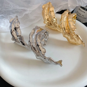 Detailed macro shot of wavy metallic leaf arm cuff in gold and silver finish