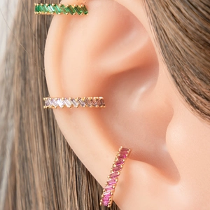 Lot de trois bagues d'oreille dorées avec cristaux colorés présentées sur un modèle