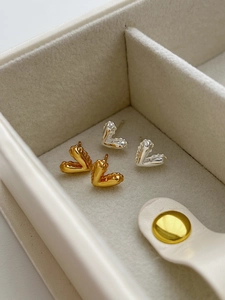Close-up of elegant gold and silver heart stud earrings with unique crinkled metal texture