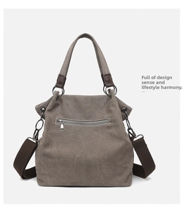 Close-up of grey canvas tote with brown fabric straps and vintage metal zipper detail