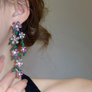 Macro view of crystal flower tassel earrings with pink and green stones on model