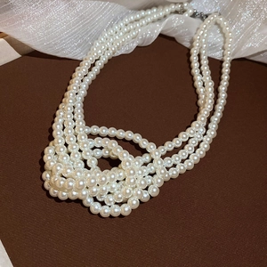 Detail shot of multi-layer white pearl necklace on brown surface with soft lighting