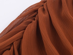 Makroaufnahme von braunem Plissee-Chiffon mit detaillierter vertikaler Faltenstruktur