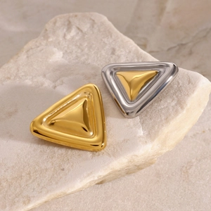 Detail view of gold and silver geometric triangle brooches on textured stone