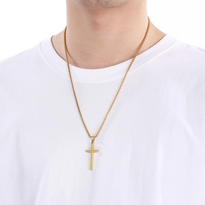 Golden minimalist stainless steel cross necklace worn by a model on a white background