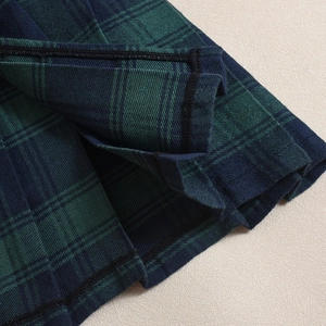 Detailed macro view of dark green plaid pleated skirt fabric with fine woven texture