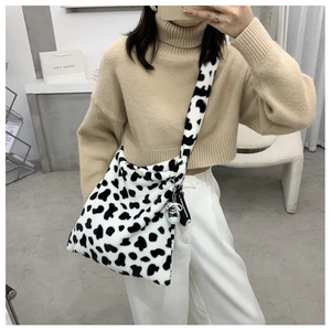 Detail of plush cow print shoulder bag with soft faux fur texture and wide strap