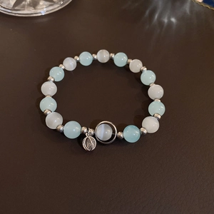 Detailed close-up of beaded bracelet with light blue cat eye stones and silver pendants