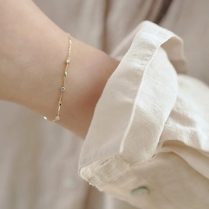 Macro shot of 14K gold-plated Mobius bracelet with diamonds on woman wrist