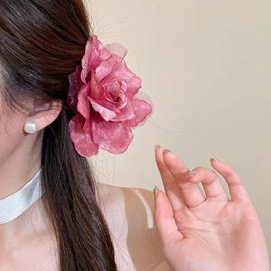 Détail d'une pince à cheveux élégante en résille rose portée par un modèle pour les vacances