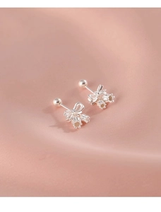 Detailed macro shot of silver lily of the valley earrings on a soft pink silk background
