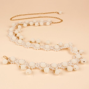 Close-up of elegant gold chain waist belt with layered white pearls and shell accents