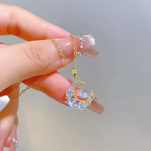 Macro shot of gold moon pendant with sparkling zircon heart on thin cable chain necklace