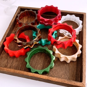 Détail macro de bracelets en acrylique multicolores à bords ondulés sur plateau bois