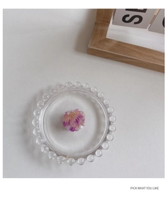 Detail of a pink shell hair clip with gold accents in a decorative glass dish