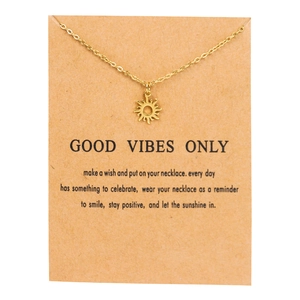 Detailed view of a gold stainless steel sun pendant necklace on a gift display card