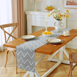 Detailed texture of grey herringbone cotton linen table runner on a wooden dining table