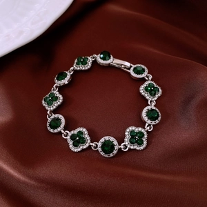 Gros plan détaillé du bracelet vintage argenté avec pierres vertes et strass sur soie