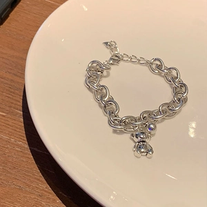 Silver bear pendant chain bracelet with round beads on a white minimalist plate