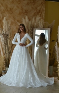 Close-up of deep V-neck white wedding dress with sequin wavy textures and long sleeves