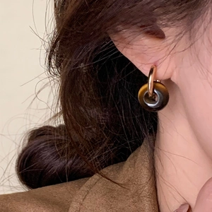 Détail de boucles d'oreilles avec pendentif rond en oeil de tigre sur un mannequin