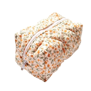 Floral quilted makeup bag with orange flowers and zipper closure on white background