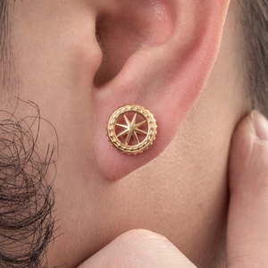 Golden round punk stud earring with star and gear pattern shown on a male model's ear