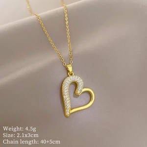 Detail of gold heart pendant with cubic zirconia and chain on brown silk fabric