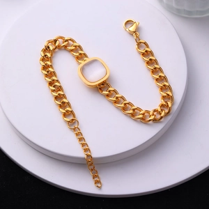 Détail d'un bracelet gourmette doré orné d'une pierre d'opale blanche carrée