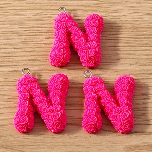 Macro detail of pink rose textured letter N charms with metal rings for DIY jewelry
