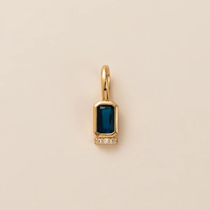 Close-up of gold pendant with rectangular dark blue gemstone and small diamonds detail