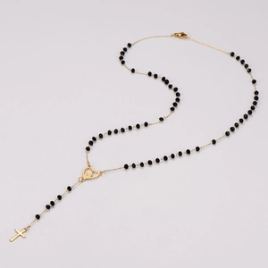 Detail view of a stainless steel rosary necklace featuring black beads and heart-shaped connector