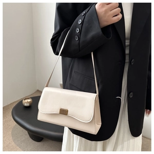 Detailed view of cream leather underarm bag with gold textured metallic buckle and strap