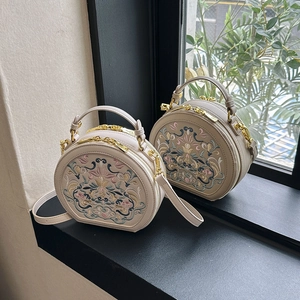 Detail of beige ethnic crossbody bag with floral embroidery and gold hardware
