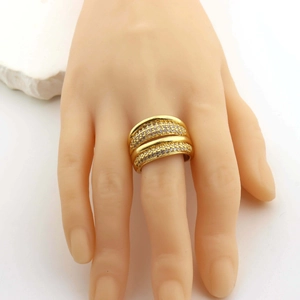 Detailed macro shot of a golden multi-layer ring featuring sparkling zircon stones on a model