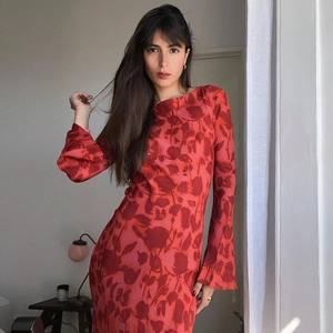 Detail shot of the red and pink floral print pattern and fabric texture on a long sleeve dress