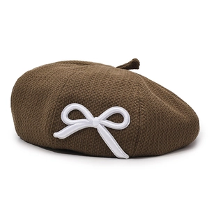 Brown knitted beret hat for women featuring a white bow embroidery on a white background